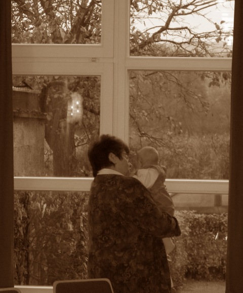Frau mit Kind schaut aus dem Fenster
