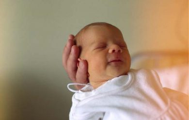 Kopf eines neugebornen Babys auf der Hand