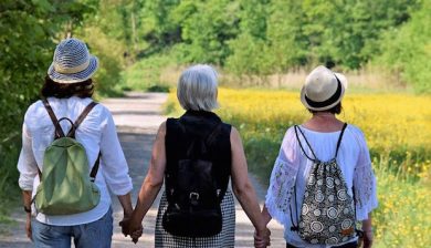 drei Frauen, die einander an der Handhalten und spazieren gehen